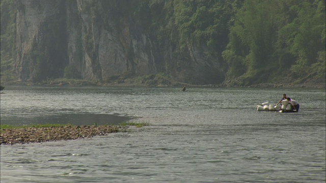 中国广西壮族自治区桂林漓江上，两名男子试图驾驶载有货物的船只视频素材