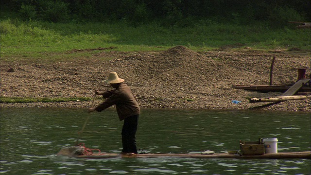 中国广西壮族自治区桂林，漓江上木筏上的男子，以推土机为背景视频素材