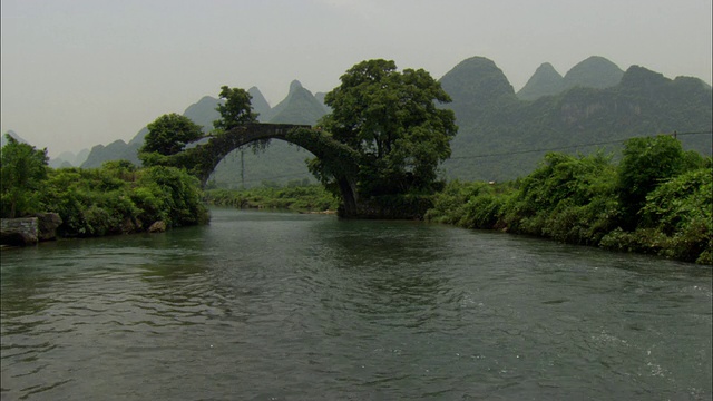 在中国广西壮族自治区桂林，以拱桥和山脉为背景的泛江视频下载