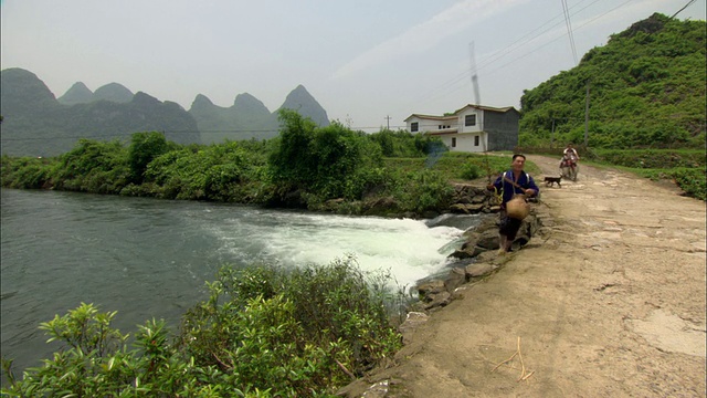 中国广西壮族自治区桂林，村里有两个人，一个在河里钓鱼，另一个在骑摩托车视频下载
