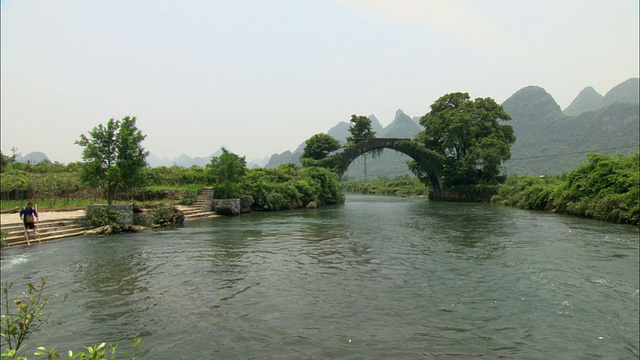 中国广西壮族自治区桂林，以拱桥和山脉为背景的WS河视频下载