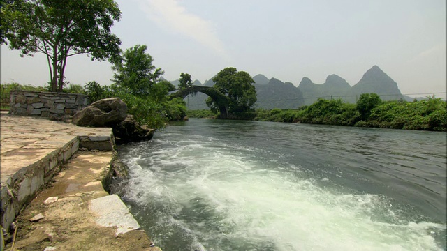 中国广西壮族自治区桂林，以拱桥和山脉为背景的WS河视频下载