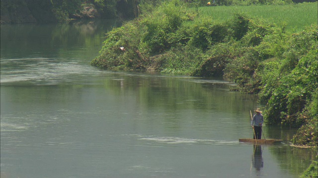 中国广西壮族自治区桂林，一名男子站在河边的木筏上钓鱼视频下载