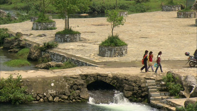 在中国广西壮族自治区桂林，以山脉为背景的WS HA ZO PAN组儿童穿过石桥视频下载