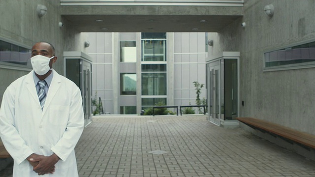 加拿大不列颠哥伦比亚省斯阔米什，一名身穿实验服、戴着流感口罩的男子站在大楼外视频素材