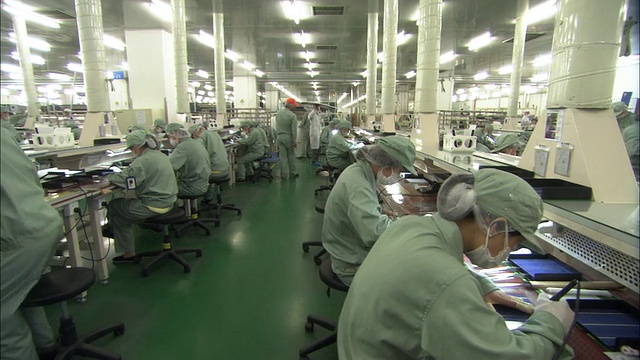 中国江苏无锡，Suntech Power Holdings工厂，一排排工人在太阳能电池板上工作视频下载