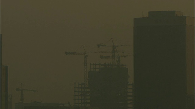 中国广西壮族自治区桂林，雾霾天空中起重机和在建摩天大楼的剪影视频下载
