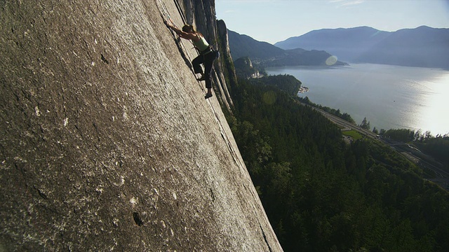 在悬崖上攀岩的女人，海岸线为背景，斯阔米什，加拿大不列颠哥伦比亚省视频下载