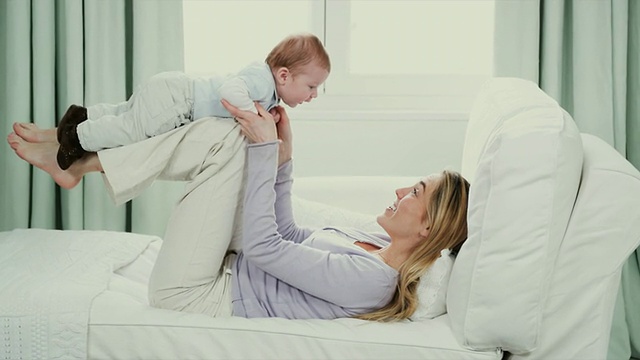 比利时布鲁塞尔，妈妈抱着小男孩(2-5个月)，躺在沙发上视频素材