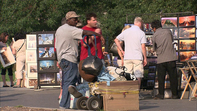在美国纽约市炮台公园，游客们一边看包一边和小贩交谈视频下载
