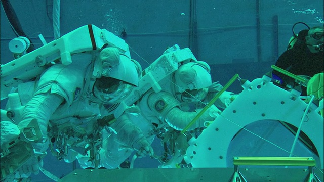 在美国德克萨斯州休斯顿的中性浮力实验室，两名宇航员在国际空间站大型模拟部件的水下工作视频素材