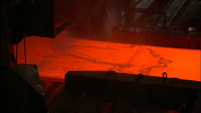 中国北京钢铁厂，水落在通过输送机的红热钢板上视频素材
