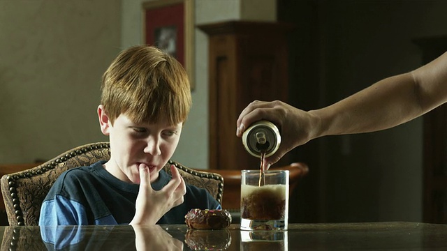 MS Boy(10-11)坐在桌子上，喝着可乐和甜甜圈，美国犹他州的美国叉子视频素材