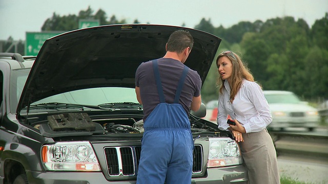 斯洛文尼亚卢布尔雅那高速公路旁，一名年轻女子正在与修理坏掉的汽车的汽车修理工交谈视频素材