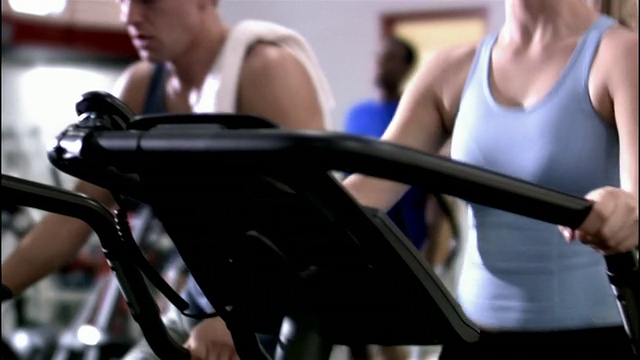 多莉在健身房用椭圆机拍摄中镜头的男人和女人视频下载