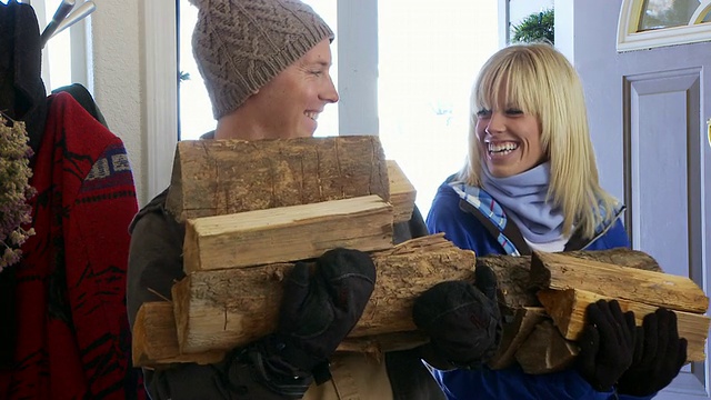 美国爱达荷州贝尔维尤，穿着冬衣的夫妇从前门把木柴运进来视频素材