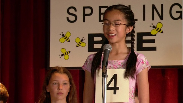 潘是拼写比赛的主持人，在麦克风上向女孩拼写单词视频素材