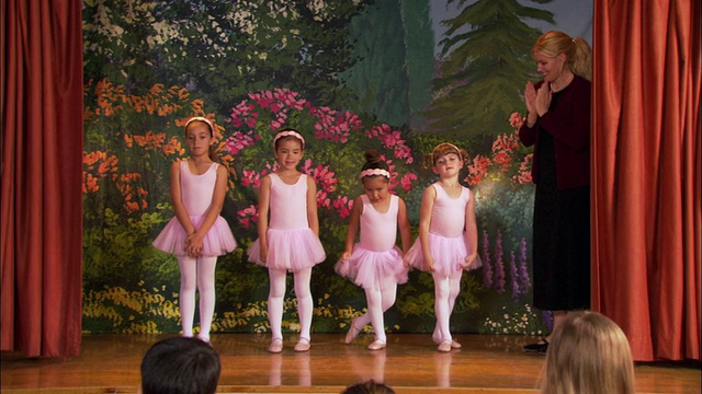 中镜头四个女孩穿着芭蕾舞裙手牵着手围成一圈跳舞/老师在舞台旁边/女孩摆姿势和行屈膝礼视频下载