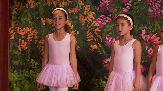 中镜头女孩在芭蕾舞裙摆姿势，转身和屈膝/平底其他三个芭蕾舞者站在舞台上视频素材