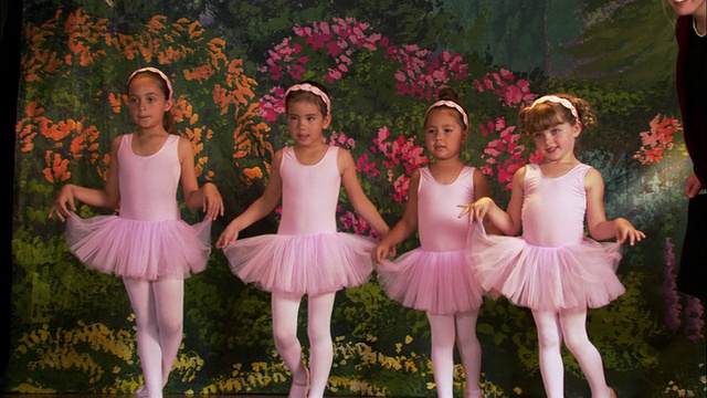 中景拍摄了四个穿着芭蕾舞短裙在舞台上摆姿势的女孩视频素材