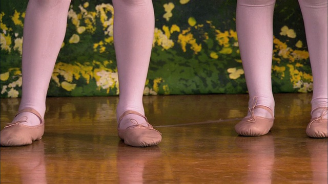 小女孩的脚在芭蕾舞鞋/倾斜中镜头女孩在舞台上跳舞视频素材