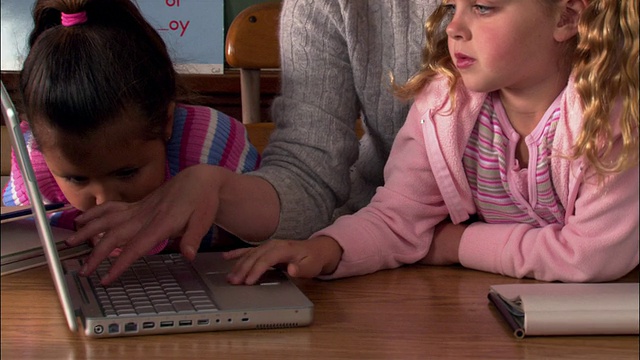 中景拍摄老师和学生在教室使用笔记本电脑视频素材