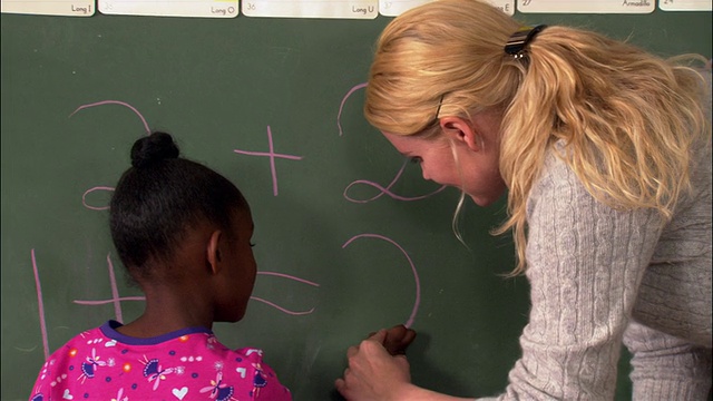中考老师在帮小女孩在黑板上写数学题视频下载