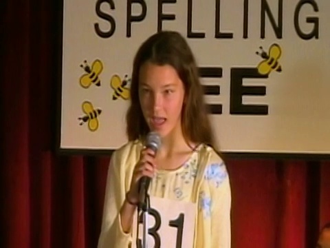 拼写比赛的主持人从讲台后面宣布单词/潘对着麦克风的女孩拼写单词/坐下来/洛杉矶，加利福尼亚视频下载