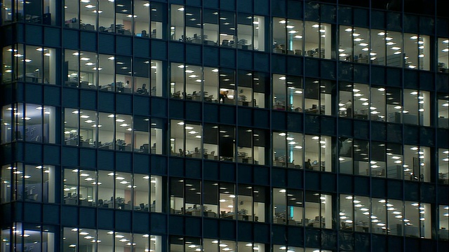 中等拍摄的窗户，办公大楼在晚上可以看到里面的人/伦敦视频下载