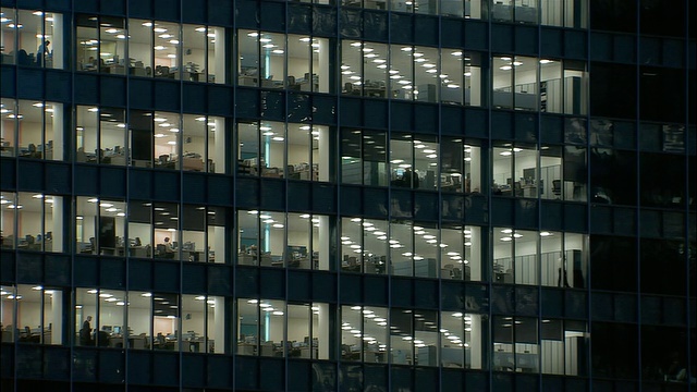 中等拍摄的窗户，办公大楼在晚上可以看到里面的人/伦敦视频素材