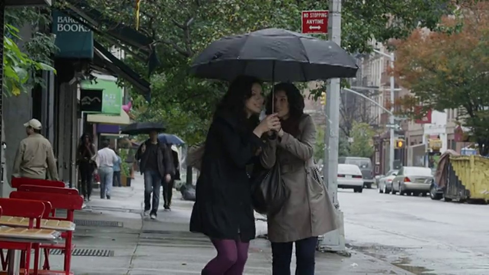 两名年轻女子离开咖啡馆，走在美国纽约市雨伞下的街道上视频素材