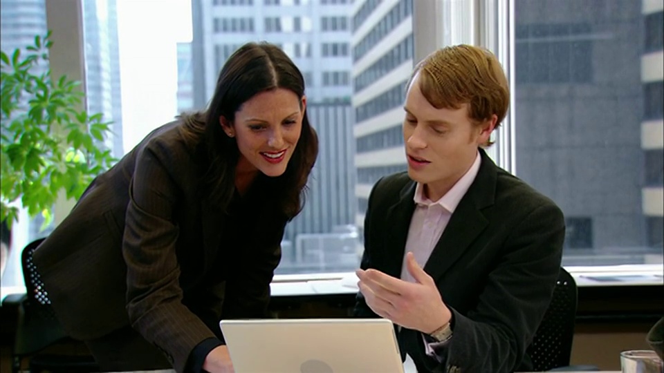 纽约，纽约，一个中等镜头的男人和一个女人在会议室里看笔记本电脑视频素材