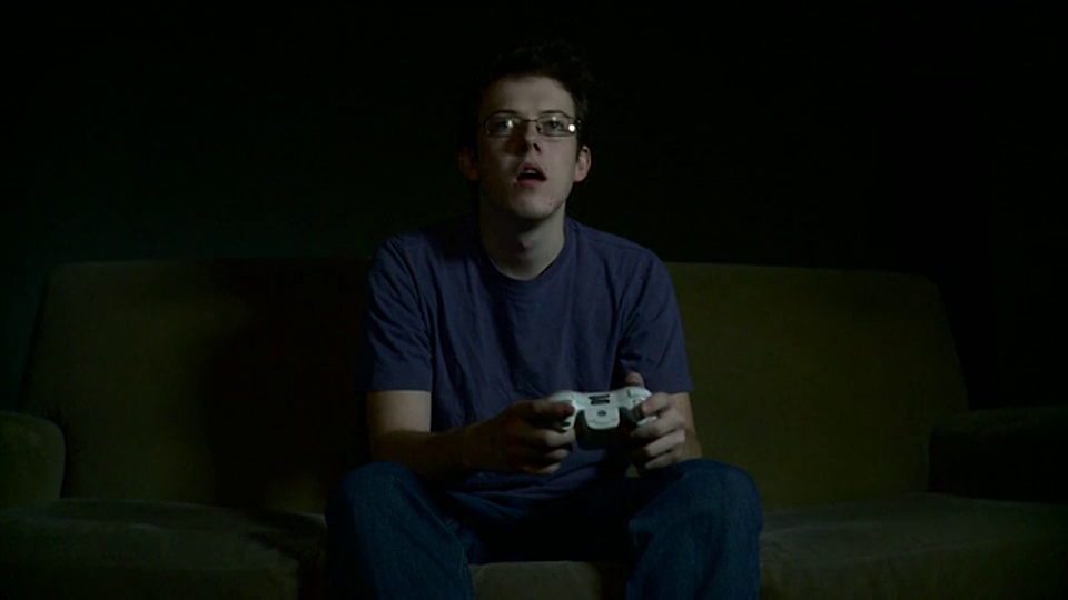 年轻男子坐在沙发上玩电子游戏/布鲁克林，纽约，美国视频下载