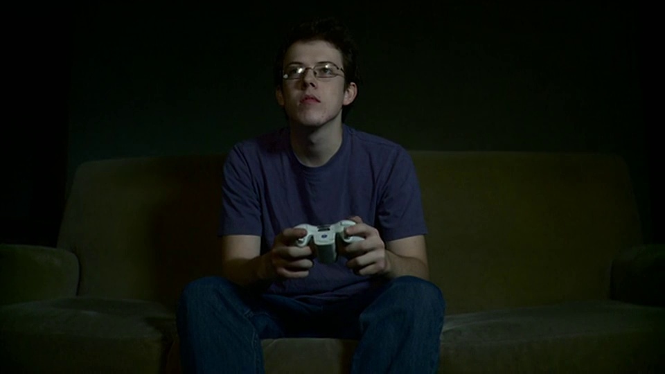 MS DS年轻男子坐在沙发上玩电子游戏/布鲁克林，纽约，美国视频下载