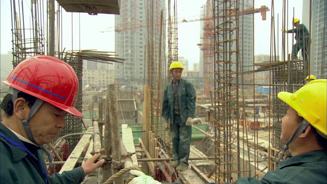 MS TU建筑工人监督水泥桶通过滑轮升到空中/广东深圳视频下载