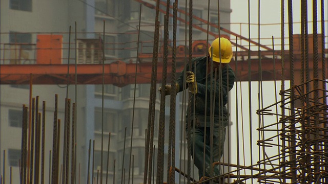 中国广东深圳，MS建筑工人从建筑工地上的铁棒网络上下来视频素材