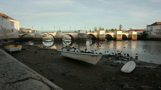 葡萄牙，阿尔加维，塔维拉，在岩石河岸上的WS船，背景是基劳河上的中世纪桥视频素材