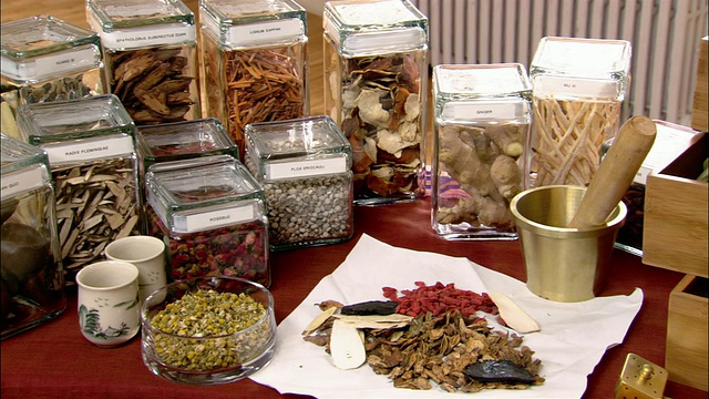 中瓶药草，研钵，杵和各种颜色的药草摆放在桌子/平底锅到药草抽屉里视频下载