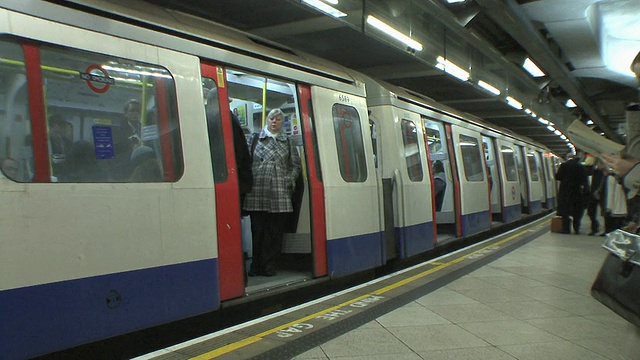 英国伦敦，威斯敏斯特地铁站，乘客进入列车。视频下载