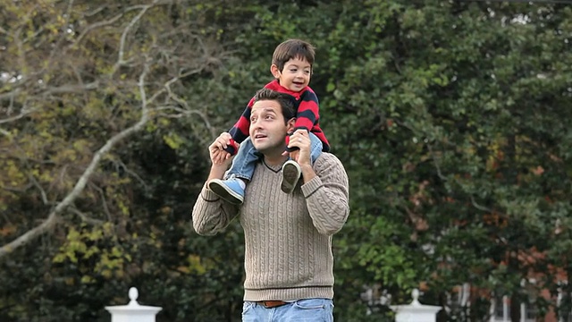 美国弗吉尼亚州里士满，父亲背着2-3岁的儿子在后院散步视频素材