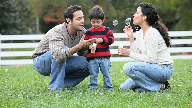 美国弗吉尼亚州里士满，父母在后院吹泡泡，儿子(2-3)蹲着视频素材