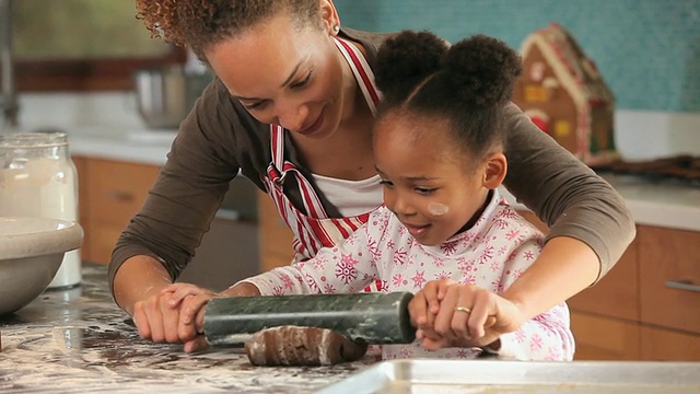 美国弗吉尼亚州里士满，母亲在厨房帮女儿(4-5岁)擀姜饼面团视频素材