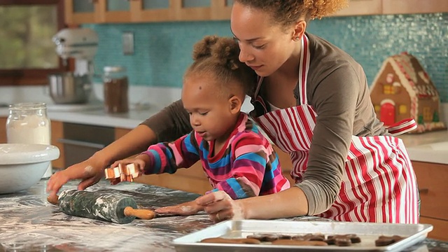 美国弗吉尼亚州里士满，母亲在厨房帮助女儿(2-3)做姜饼视频素材