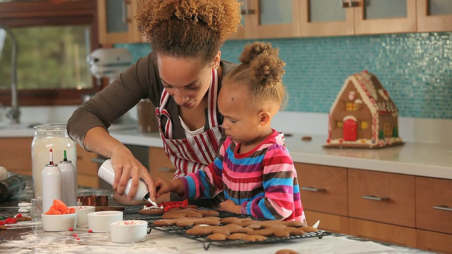 美国弗吉尼亚州里士满，母亲和女儿(2-3)在厨房装饰姜饼视频素材