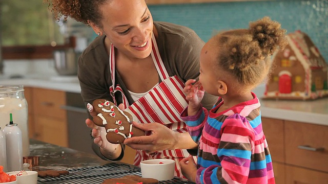 美国弗吉尼亚州里士满，母亲和女儿(2-3)在厨房里装饰姜饼视频素材