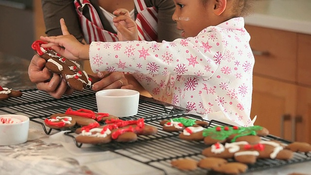 美国弗吉尼亚州里士满，母亲和女儿(4-5岁)在厨房里装饰姜饼视频素材