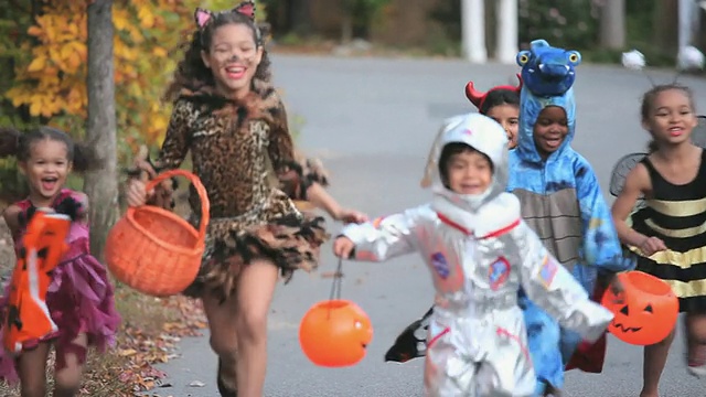 一群孩子(2-7)穿着万圣节服装在美国弗吉尼亚州里士满的街道上奔跑。视频下载