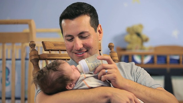 在美国弗吉尼亚州里士满的育婴室，父亲抱着奶瓶喂养男婴(2-5个月)。视频素材