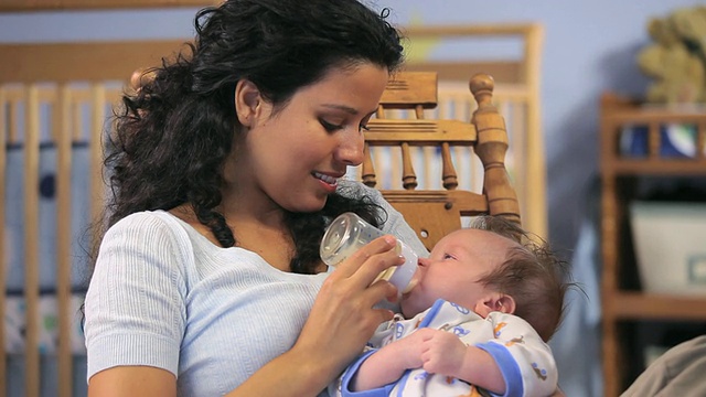 美国弗吉尼亚州里士满育婴室，母亲用奶瓶喂养2-5个月大的男婴。视频素材