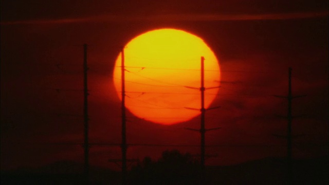 在前景/怀俄明州，美国，橙色的太阳正在慢慢落下，高压输电线路的剪影视频下载